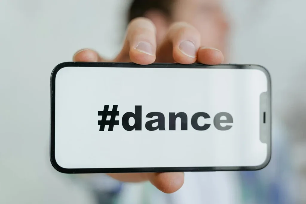Hello world! — Close-up of a phone screen displaying the #dance hashtag, held by an adult.