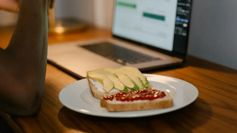 A workspace setup with avocado toast next to a laptop, perfect for remote work inspiration.