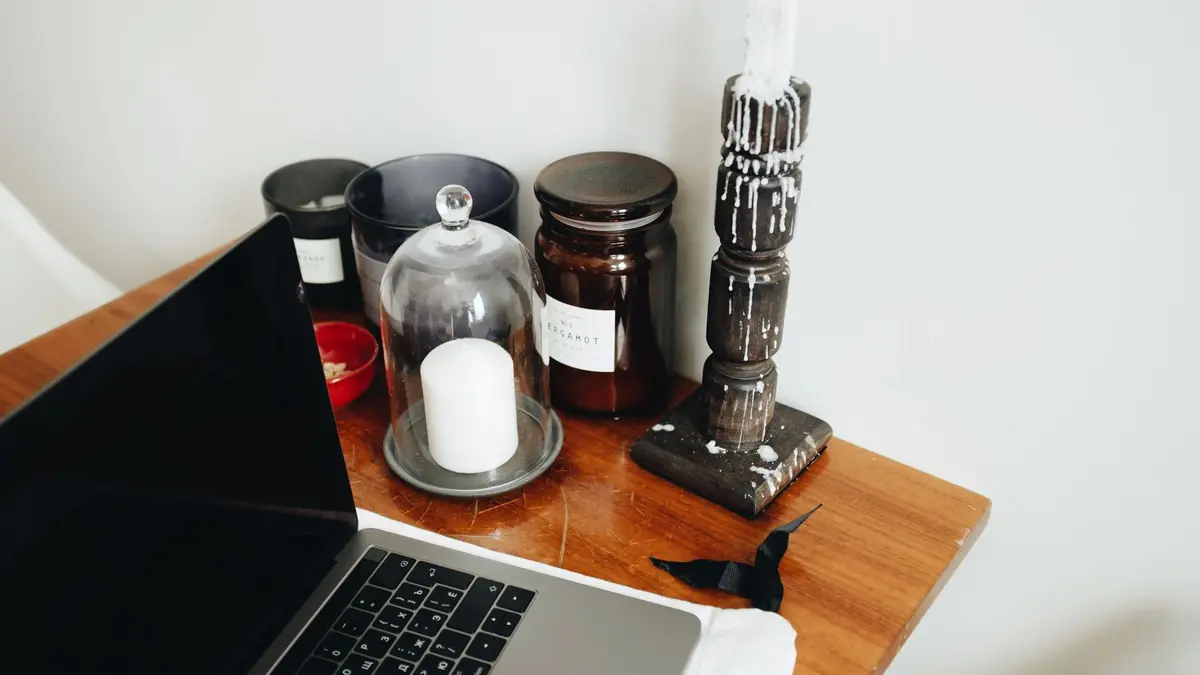 Freelance workspace with laptop and various black aromatic candles in glass jars and wooden candlest