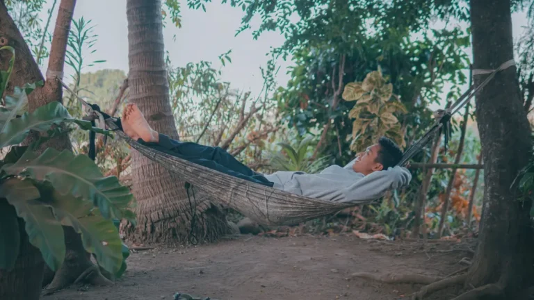A young man enjoying a peaceful moment in a hammock surrounded by lush greenery.