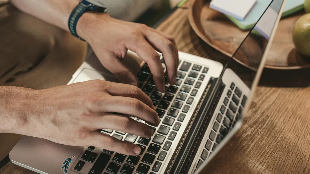 Close-up of hands typing on a laptop, capturing a productive indoor workspace vibe.